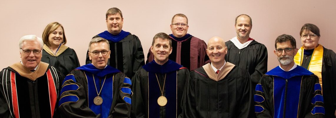 Faculty colleagues Dr. Doug Smith, center of second row, and Mary Rittenhouse, at right back row, joined standing, from left, Jennifer McConville, Dr. Brad Ramsdale and Eric Reed at the 2016 NCTA Commencement. Front row, from left, is Regent Bob Phares of North Platte, now-UNL Chancellor Ronnie Green (IANR VIce Chancellor last year), University President Hank Bounds, Nebraska Governor Pete Ricketts and NCTA Dean Ron Rosati.
