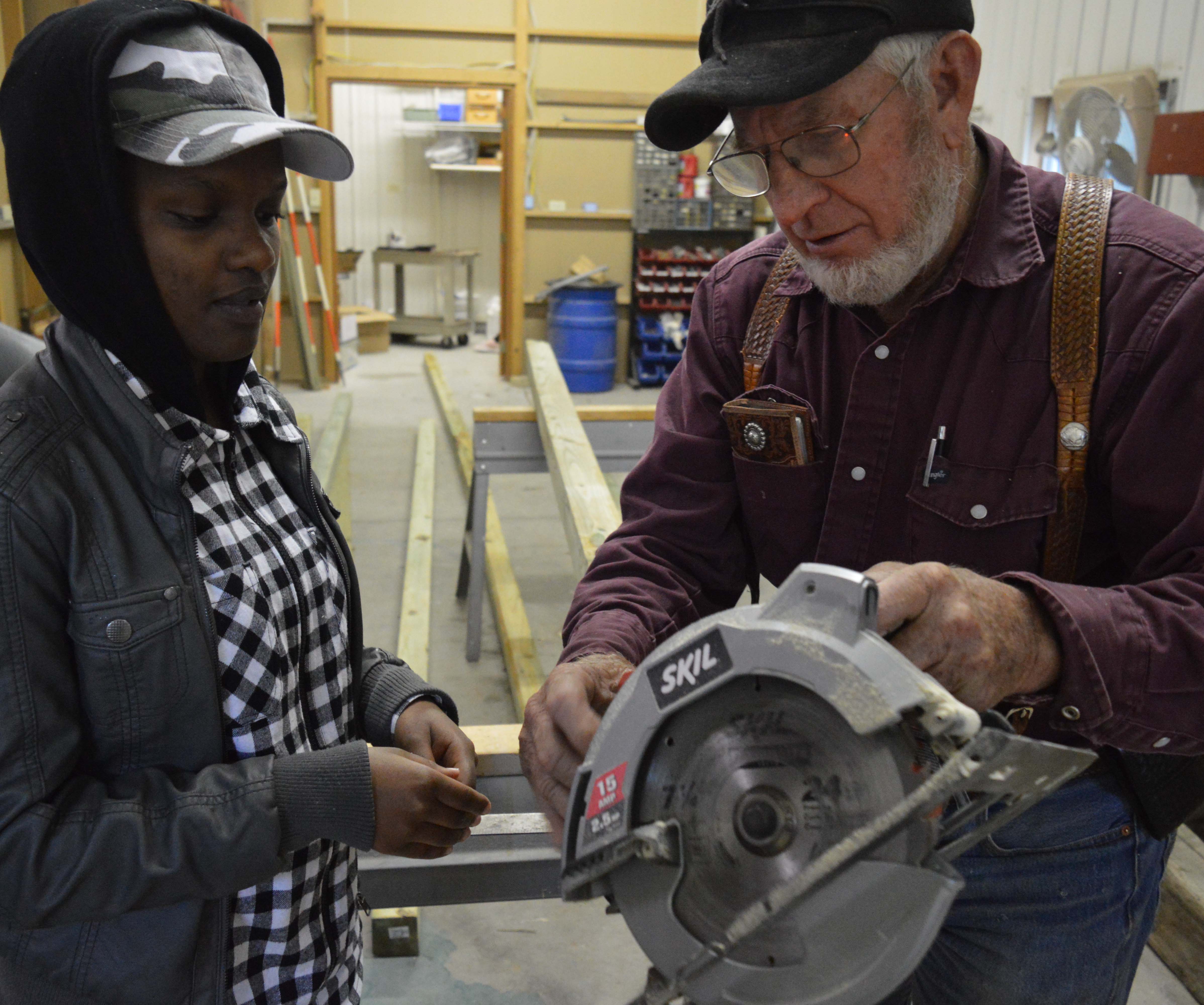 CUSP student Yvonne Ingabire receives safety instructions before operating a power saw in a construction class taught by Roy Cole. He designed a sheep shed which students are building for the NCTA campus farm. (Crawford/NCTA News)