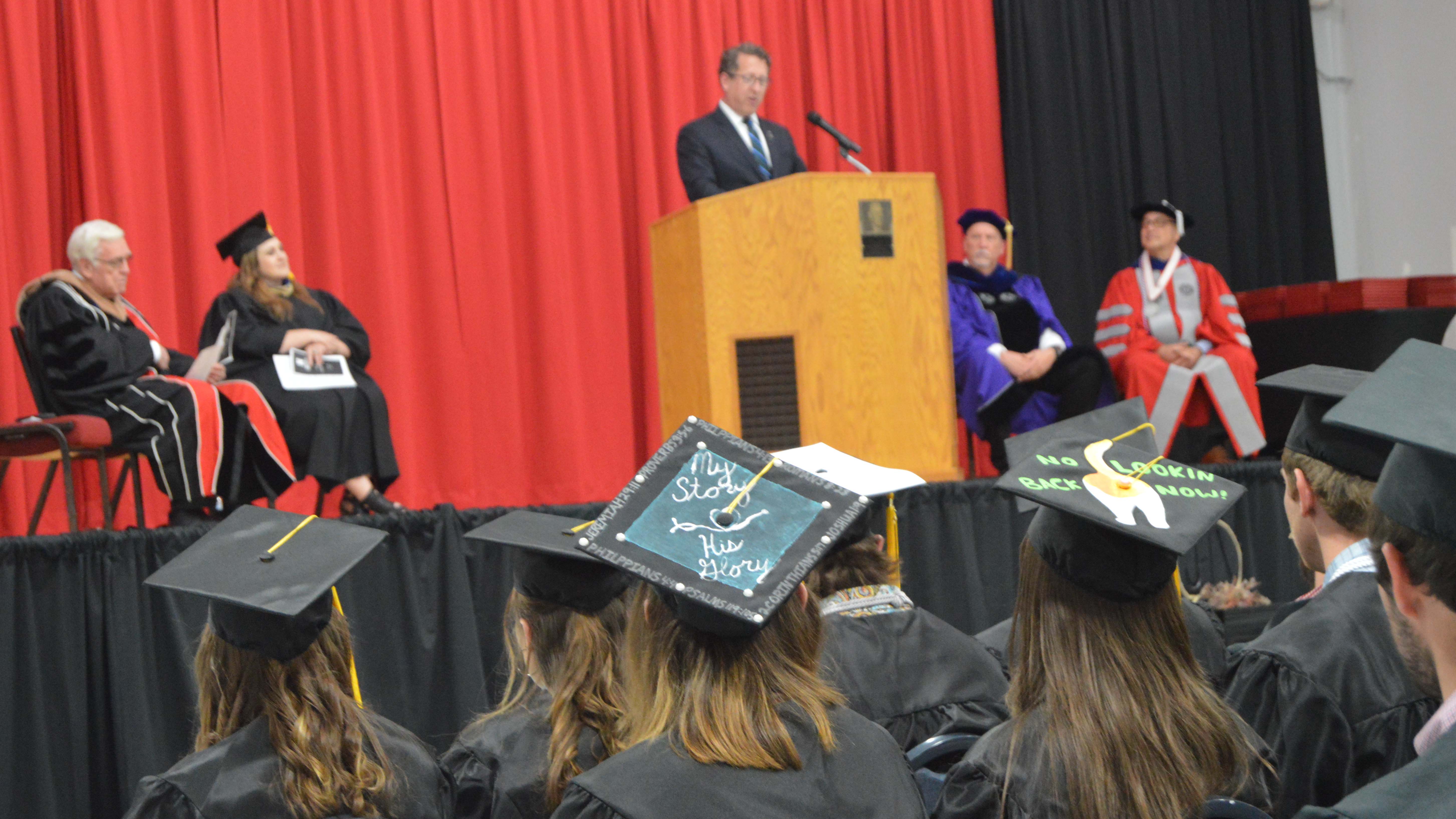 Congressman Adrian Smith delivered the 2022 Commencement Address at the Nebraska College of Technical Agriculture. From left, Bob Phares, Jennifer McConville, Larry Gossen and Mike Boehm. The top of a mortarboard says, “My Story. His Glory.” (Mary Crawford / NCTA News Photo)