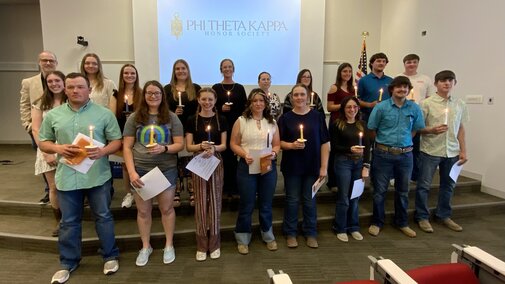Students participate in PTK Ceremony 2025. Students are holding their awards and candles.