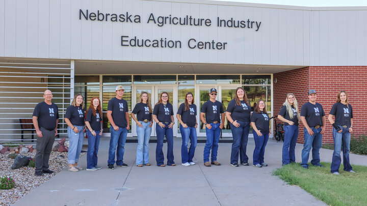 Residence Life Staff and students in matching shirts stand outside the Nebraska Agriculture Industry Education Center.