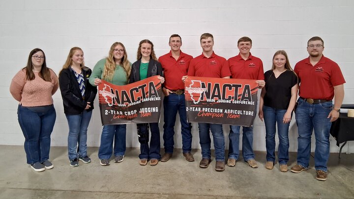 NCTA Student team photographed at Illinois contest with their two awards banners for agricultural competition wins.