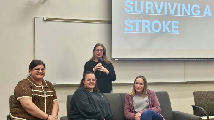 Panel discussion on stroke recovery with four seated individuals and a presenter speaking.