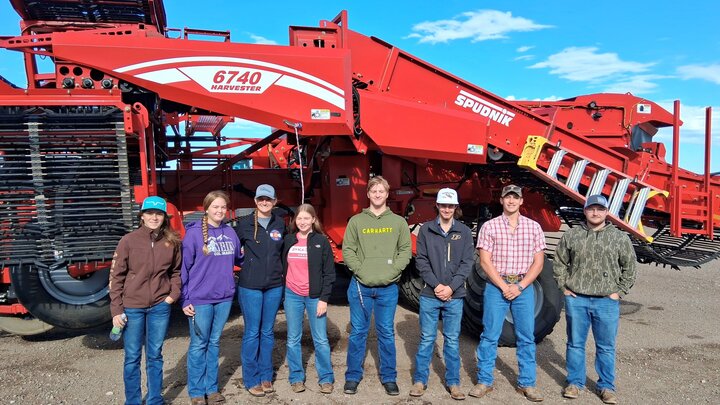 From left to right — Wyatt Ozenbaugh of Ohiowa, Nebraska; Aaron Underwood of Esbon, Kansas; Jada Eilert of Jewell, Kansas; Paige Davis of Bartlett, Kansas; Hailey Loutzenhiser of Flagler, Colorado; Mason Semler of Friend, Nebraska; KaCee Jo Saffer of Arriba, Colorado; and Conrad Burrow of Wheatland, Wyoming stand in front of the red 6740 harvester at Frenchman Valley Produce in Imperial, Nebraska. Their field trip offered a hands-on look at modern potato production, processing, and the region’s vital role i