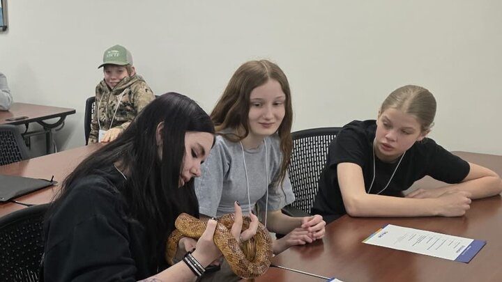 Junior High students hold and observe a snake at the Expanding Your Horizons event while NCTA faculty talk about careers in veterinary science. 