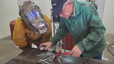 Chuck Hatzenbuehler of Reinke Manufacturing examines welds by Aggie Trever Muellenberg, North Platte, during a test for American Welding Society certification. (M. Crawford / NCTA photo)